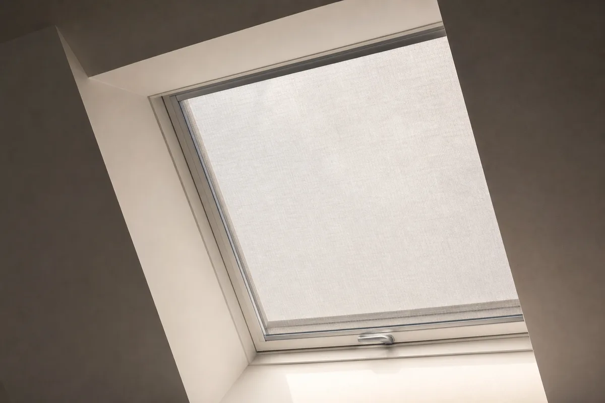 Store extérieur pare-soleil déployé sur une fenêtre de toit dans un comble aménagé baigné de lumière